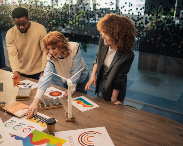 Multicultural businesspeople standing at modern office and working on paperwork and analysis for renewable energy resources technology. Diverse environmentalists developing clean energy technology.
